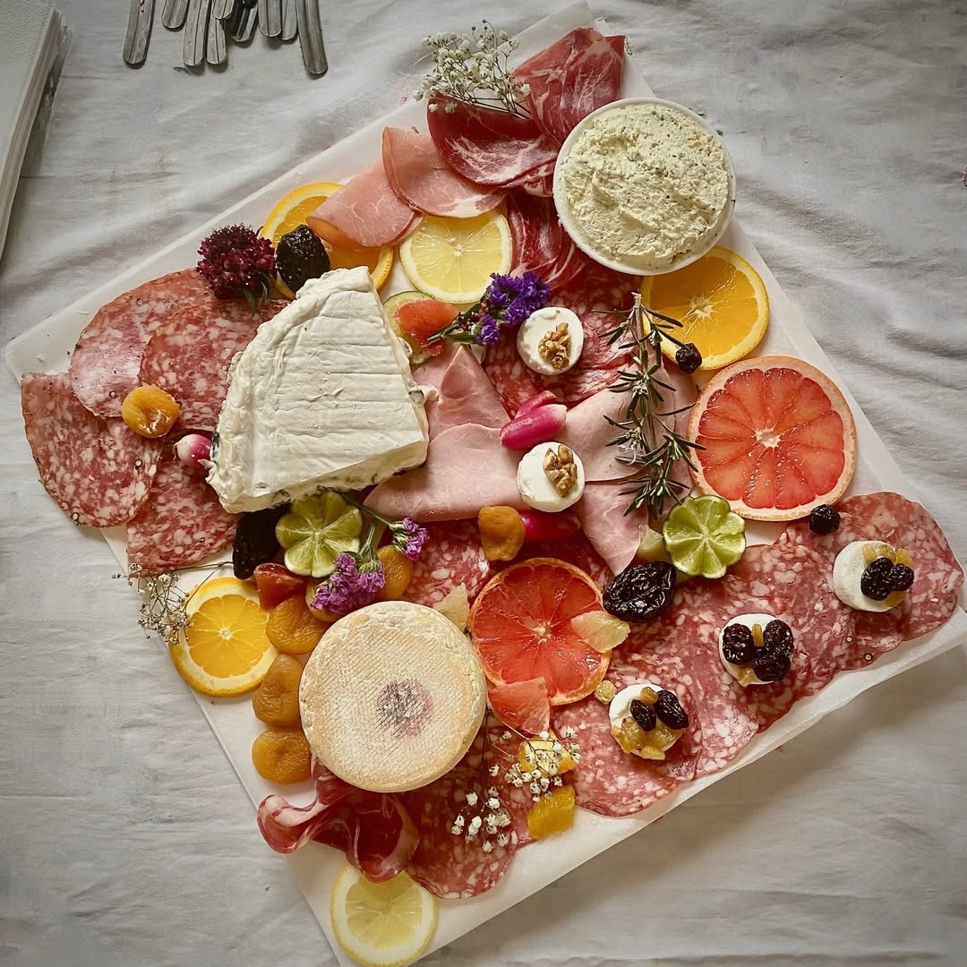Planche charcuterie et fromages avec fleurs et agrumes